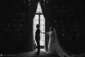A wedding couple standing in front of a bookcase at a private club in Manhattan.