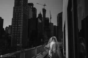 A bride is standing on a private club's balcony overlooking Manhattan.
