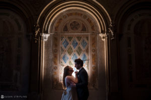 A couple, the bride and groom, standing in front of an ornate archway during their private club wedding in Manhattan.