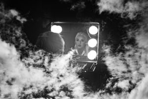 A black and white photo of a woman in a mirror at a wedding.