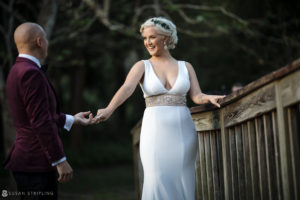 A bride and groom on their wedding day, holding hands on a wooden bridge at Quantum Leap Winery.