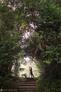 A bride and groom sharing a joyful moment on the steps of Quantum Leap Winery during their wedding ceremony in a serene wooded area.