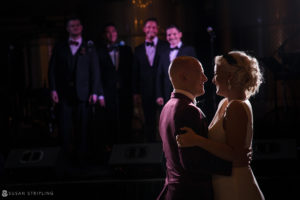 A newlywed couple sharing their first dance at a wedding reception in front of a band.