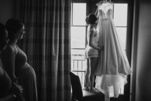A bride admiring her wedding dress in front of a window at Alfond Inn.