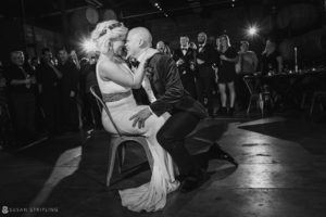 The bride and groom sharing a tender kiss at their breathtaking Quantum Leap Winery wedding reception, surrounded by an adoring crowd of people.