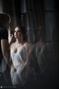 A bride getting ready for her Wedding in front of a mirror at the Alfond Inn.