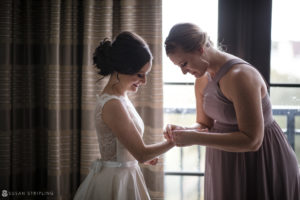 At the Alfond Inn, a bride gracefully assists her bridesmaid with the placement of her wedding ring.