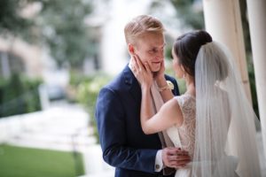 A bride and groom hugging in front of a pillar at their Alfond Inn Wedding.