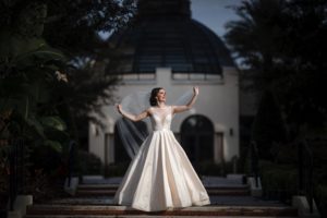 A bride in a wedding dress standing on the steps of the Alfond Inn.
