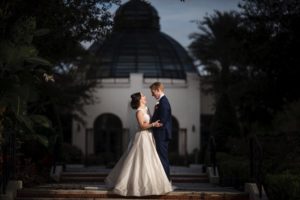 A bride and groom standing in front of the Alfond Inn at dusk on their wedding day.