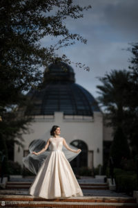 A bride in a wedding dress standing in front of the Alfond Inn.