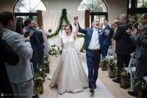 A bride and groom walk down the aisle at their wedding held at the Alfond Inn.