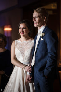 A bride and groom smile at each other during their wedding ceremony at the Alfond Inn.