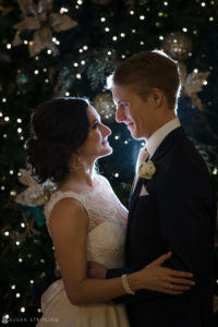 An enchanting Alfond Inn wedding captures a bride and groom radiating love in front of a beautifully adorned Christmas tree.