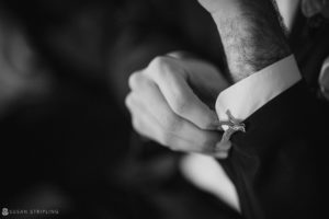 A black and white photo of a man adjusting his cufflinks at a winter wedding at Front and Palmer.