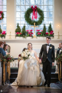 A bride and groom having a magical winter wedding at Front and Palmer, walking down the aisle of a church.