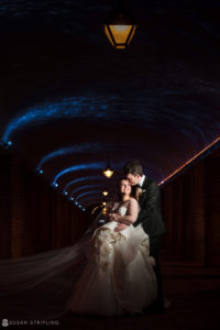 A bride and groom posing in a tunnel under a blue light at their Winter wedding at Front and Palmer.