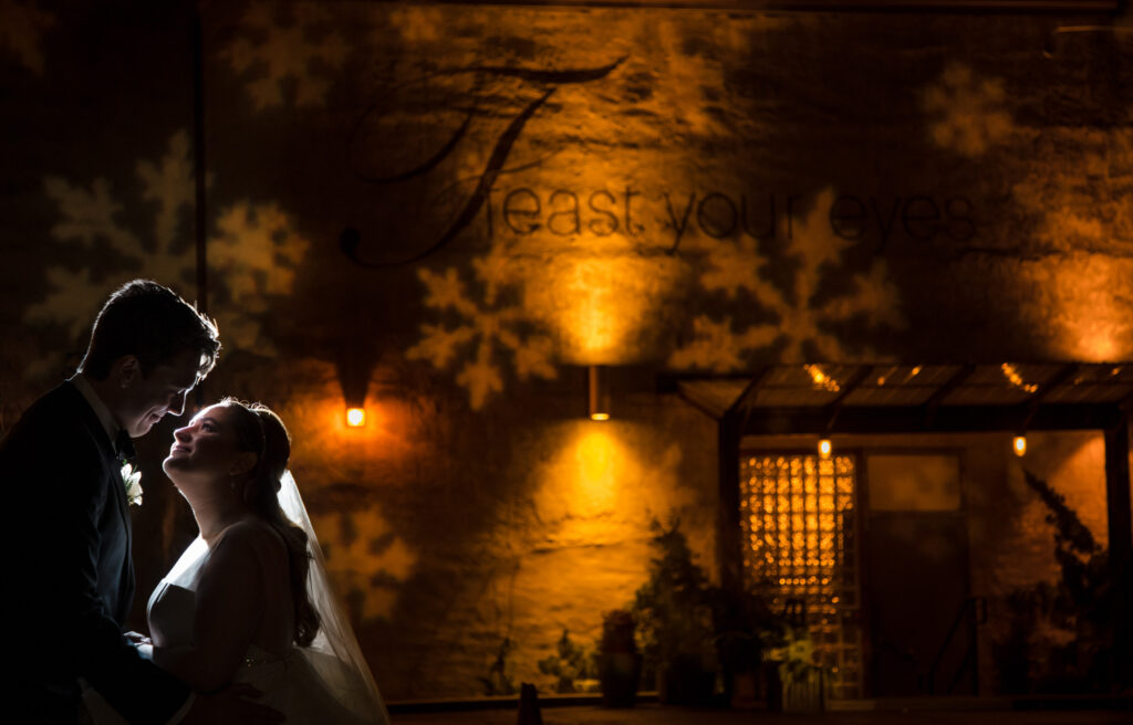 A Winter Wedding at Front and Palmer - A bride and groom share a intimate kiss in front of a mesmerizing snowflake projection.