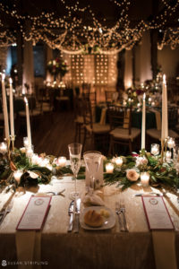 A Front and Palmer wedding table set with candles and greenery for a winter wedding.