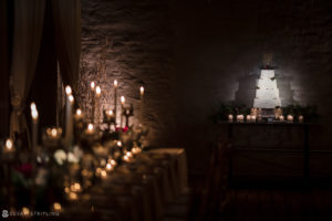 A winter wedding cake in a dark room with candles at Front and Palmer.