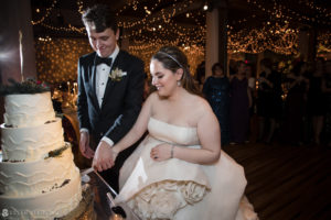 A Front and Palmer bride and groom celebrating their winter wedding by cutting their wedding cake.