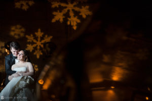 A Winter Wedding couple posing in front of snowflakes at Front and Palmer.