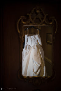 A wedding dress hanging in Philly's Union League, reflecting in a mirror.