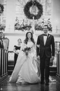 A black and white photo of a bride and groom walking down the aisle at Philly's Union League on their wedding day.