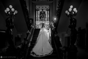 A bride and groom standing on a staircase at Philly's Union League, captured in black and white.