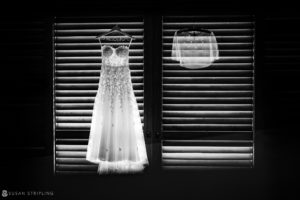 A wedding dress hanging in a window with shutters at the Ocean Club in the Bahamas.