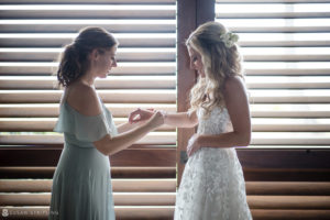 At the Ocean Club in the Bahamas, a bride is joyfully placing her wedding ring on her bridesmaid's finger.