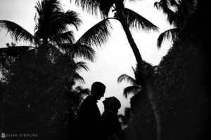 A black and white photo of a couple kissing under palm trees at the Ocean Club in the Bahamas.