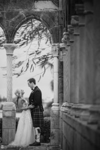A bride and groom in kilts having a wedding ceremony at the Ocean Club in the Bahamas, standing in front of arches.
