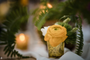 A golden ocean club vase with a yellow flower in it at a wedding in the Bahamas.