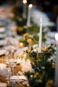 At the enchanting Ocean Club in the Bahamas, a beautifully adorned long table awaits. Luminous candles cast a romantic glow, while delicate blooms add an exquisite touch. This picturesque setup is