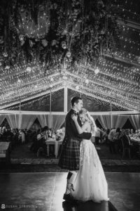 A bride and groom dance at their wedding in the Bahamas' Ocean Club, under romantic lights inside a tent.