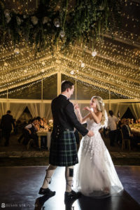 A bride and groom dancing at the Ocean Club Bahamas wedding, under lights in a tent.