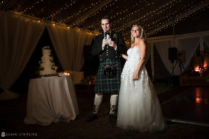 A bride and groom in traditional Scottish attire, including kilts, standing in front of a tent at their wedding ceremony held at the Ocean Club in the Bahamas.