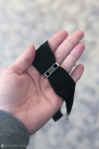 A Grand Master's hand holding a black necktie.