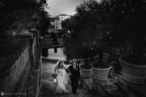 A bride and groom walking down the stairs at Vizcaya in a black and white wedding photo.