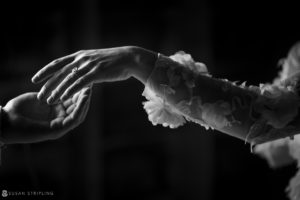 A black and white photo of a bride and groom holding hands, captured by a WPPI Grand Master photographer.