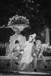 A black and white photo of a group of children sitting on a bench at Vizcaya, captured during a vow renewal or wedding celebration.