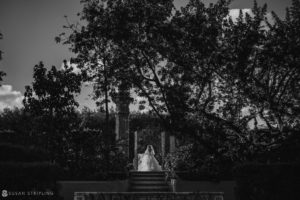 A bride is gracefully descending a staircase in a black and white photo at Vizcaya for her wedding.
