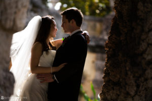 A bride and groom embrace in front of a stone wall during their Vizcaya wedding.