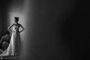 A bride in a wedding dress is standing in a dark room at Nassau Inn Wedding.