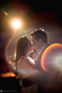 A bride and groom kiss during their Vizcaya wedding ceremony in front of a bright light.