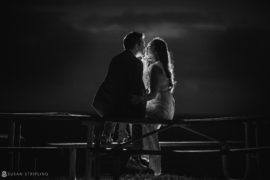 A bride and groom sharing a romantic kiss on a bench at night during their Vizcaya wedding.
