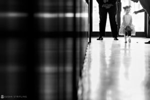 Black and white photo of a little girl standing in a hallway.