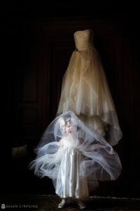 A little girl is standing in front of a wedding dress displayed by a Grand Master.