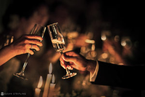 Two people toasting champagne glasses at a wedding captured by a Grand Master photographer.